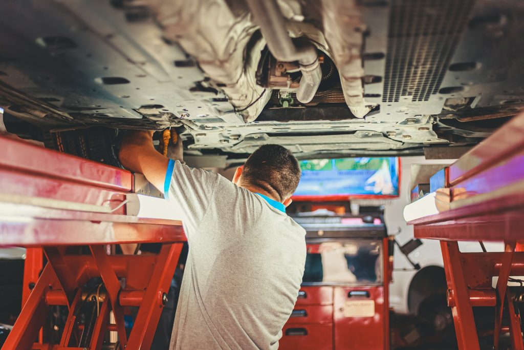 Mechanic Checking Under Car in Garage Testing MOT